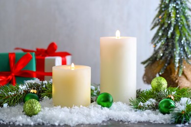 Photo of Burning candles, baubles and other Christmas decor on table