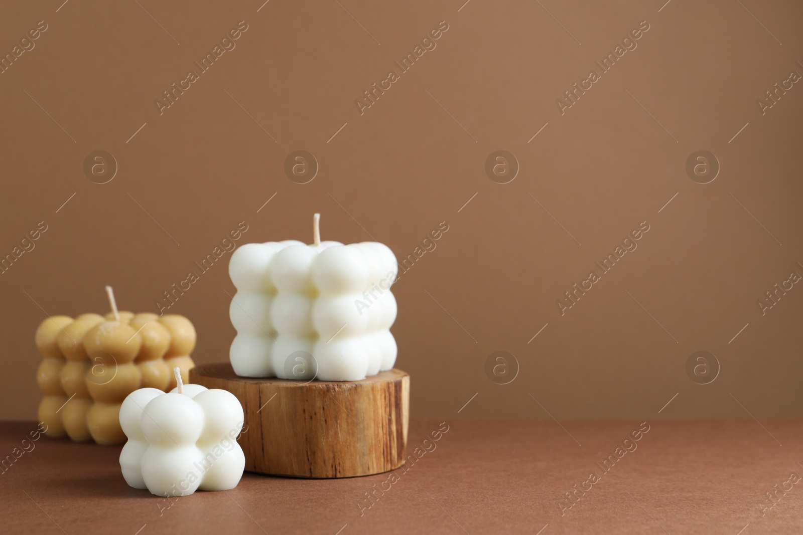 Photo of Beautiful bubble candles on brown table, space for text