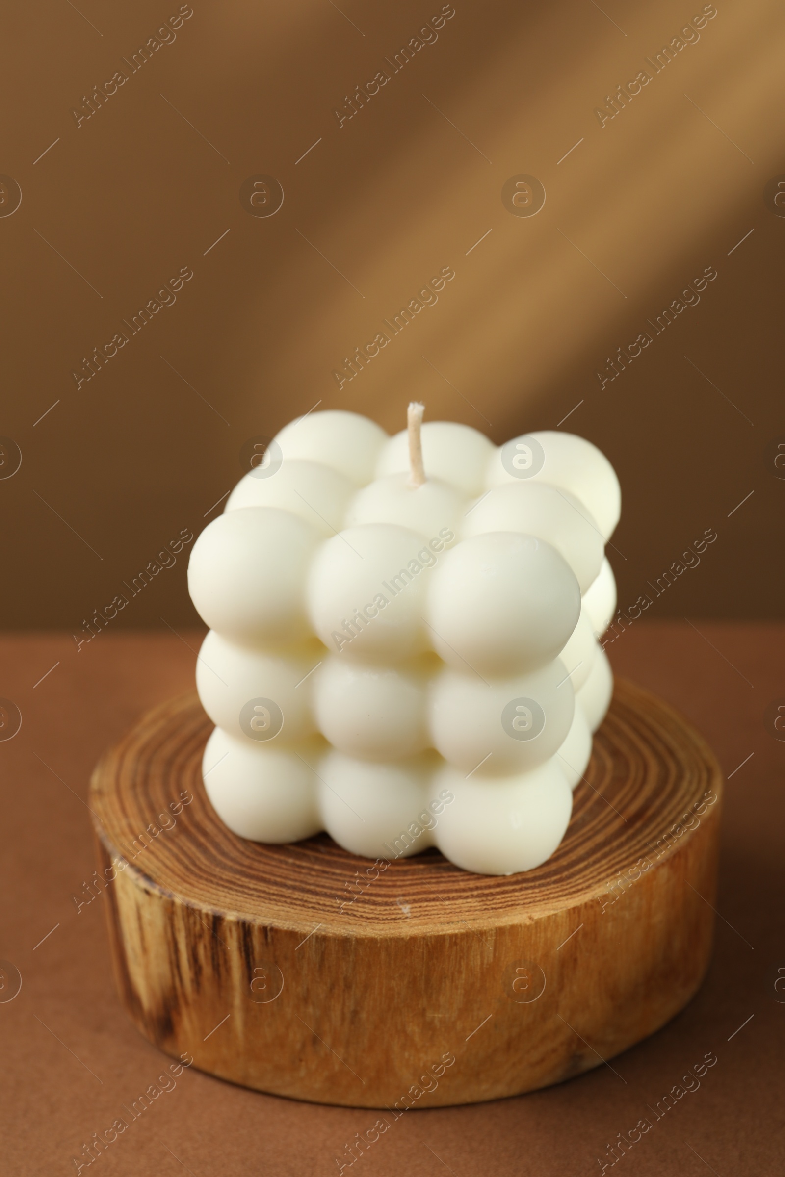 Photo of One beautiful bubble candle on brown table, closeup