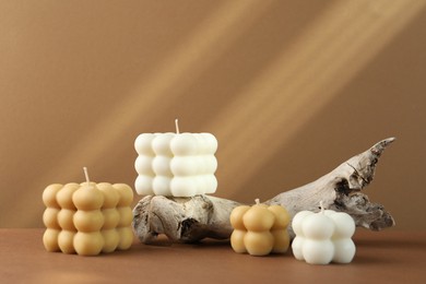 Photo of Beautiful bubble candles and snag on brown table