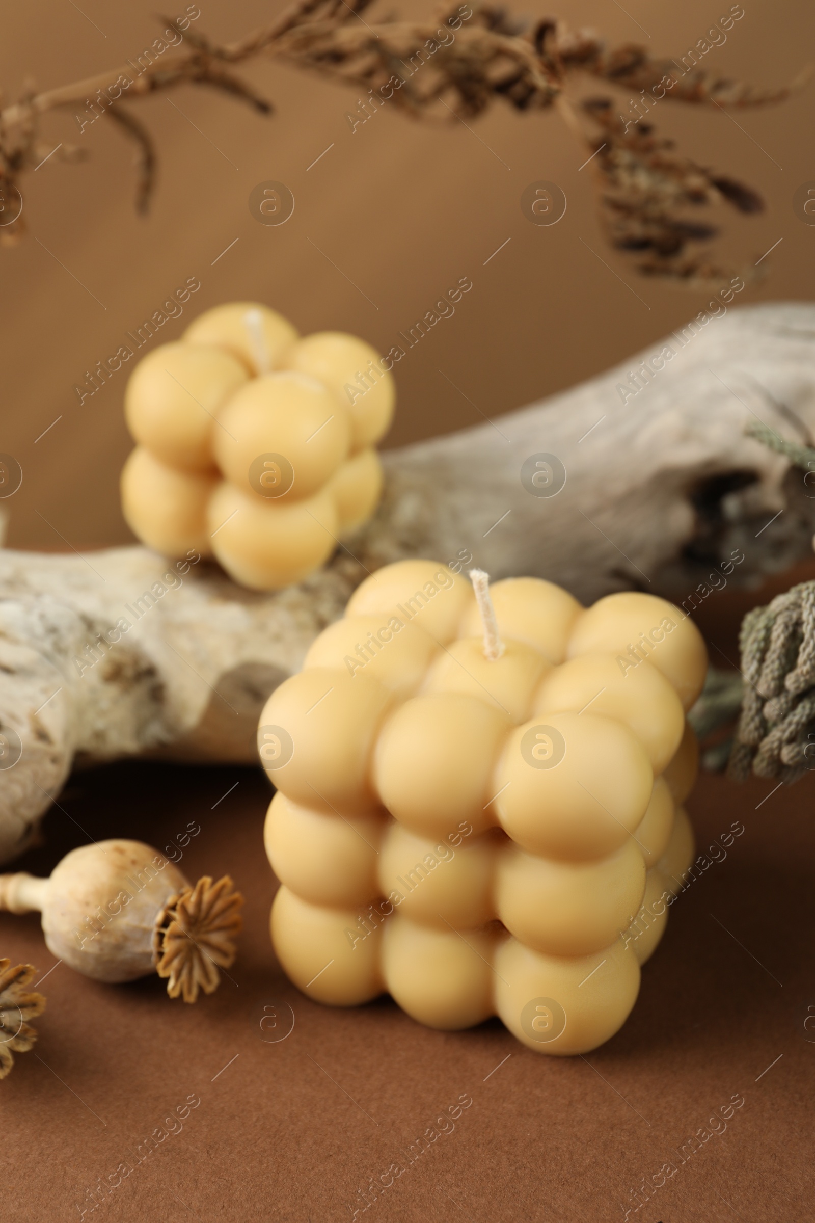 Photo of Beautiful bubble candles and snag on brown table, closeup