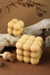 Photo of Beautiful bubble candles and snag on brown table, closeup