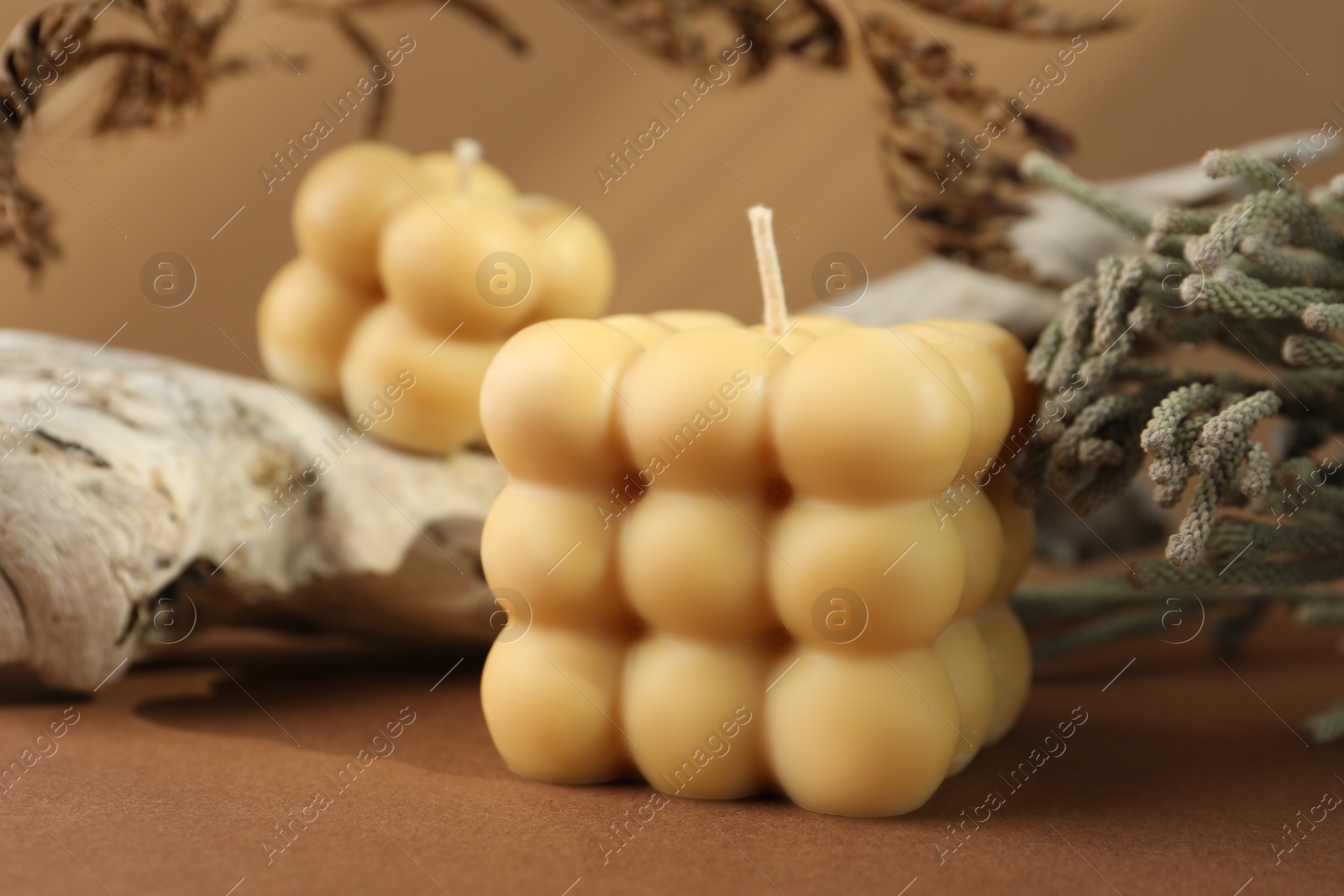 Photo of Beautiful bubble candles and snag on brown table, closeup