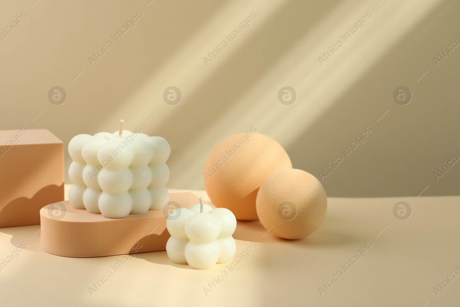 Photo of Beautiful bubble candles and geometric figures on beige background