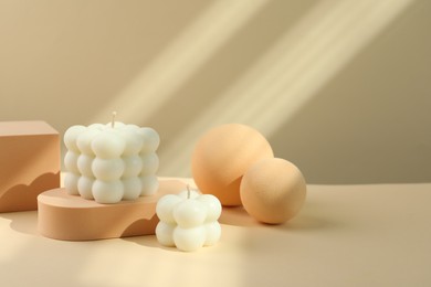 Photo of Beautiful bubble candles and geometric figures on beige background