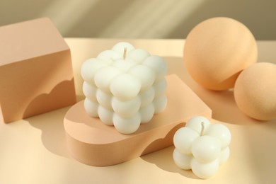 Photo of Beautiful bubble candles and geometric figures on beige background