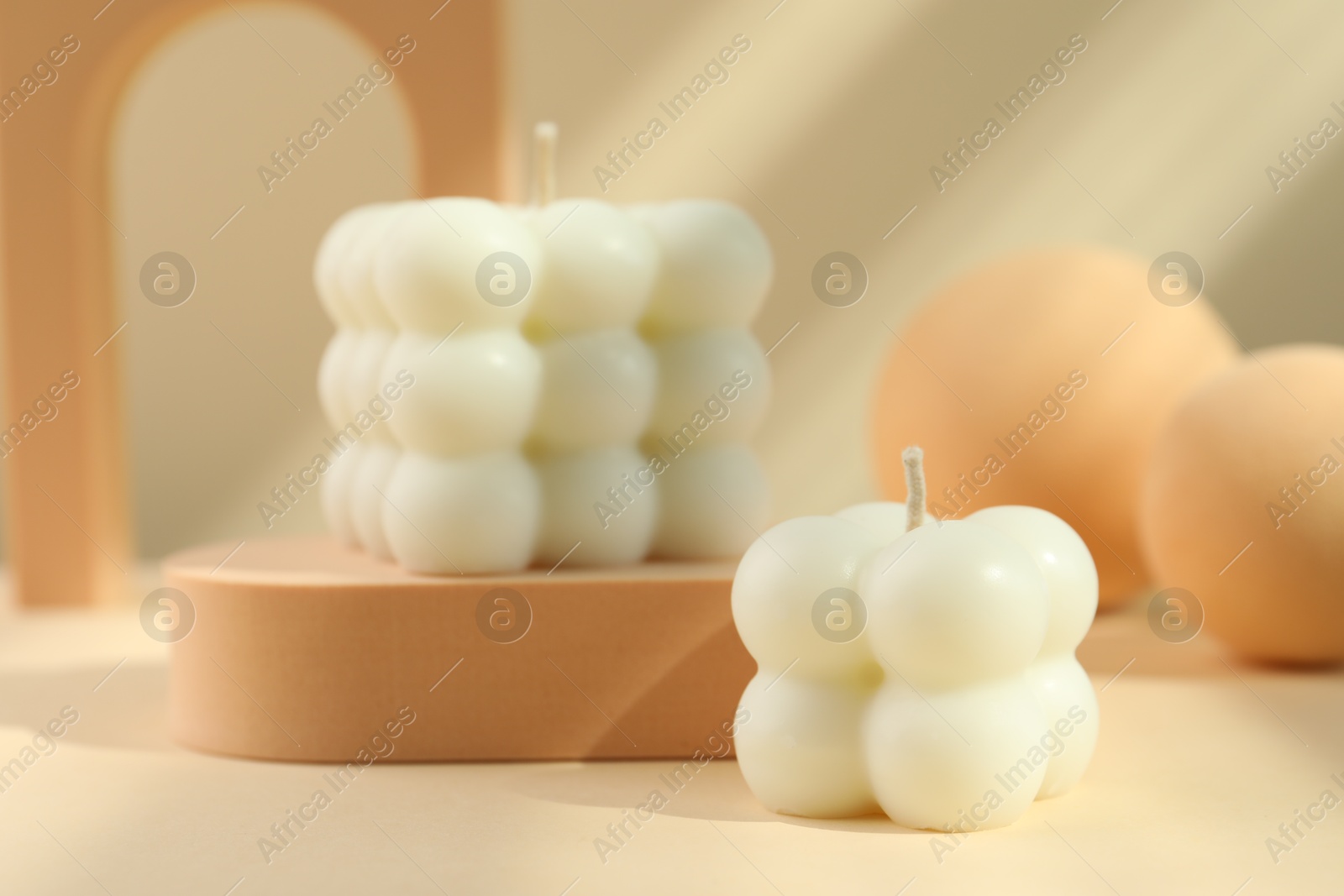 Photo of Beautiful bubble candles and geometric figures on beige background, closeup