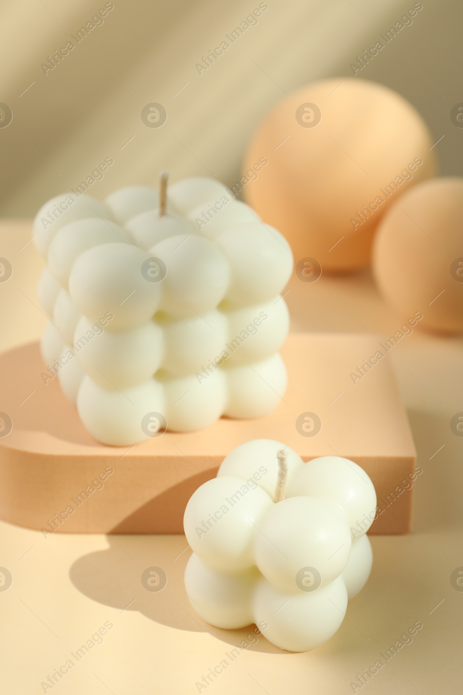 Photo of Beautiful bubble candles and geometric figures on beige background, closeup