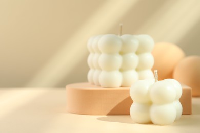 Photo of Beautiful bubble candles and geometric figures on beige background