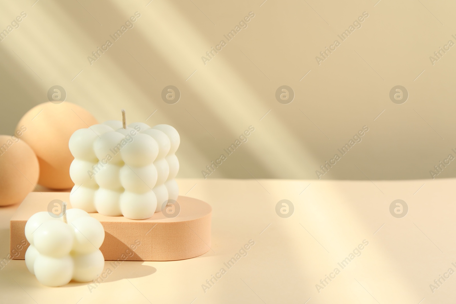 Photo of Beautiful bubble candles and geometric figures on beige background, space for text