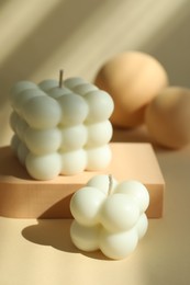 Photo of Beautiful bubble candles and geometric figures on beige background, closeup