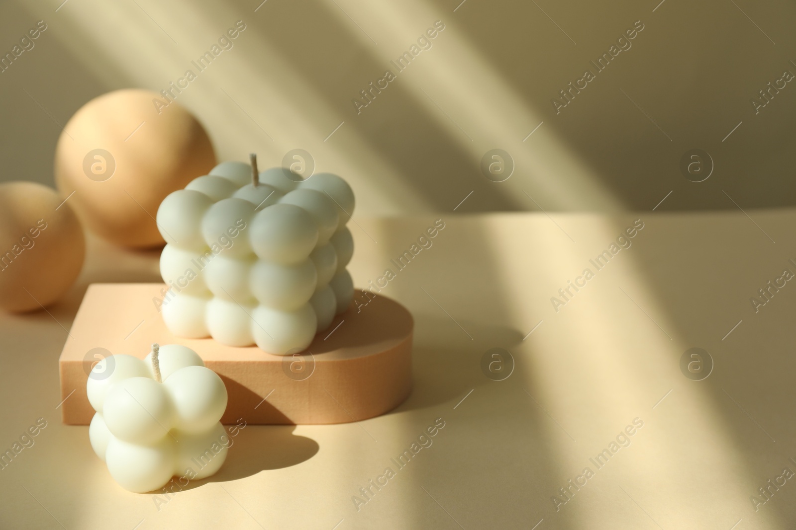 Photo of Beautiful bubble candles and geometric figures on beige background, space for text