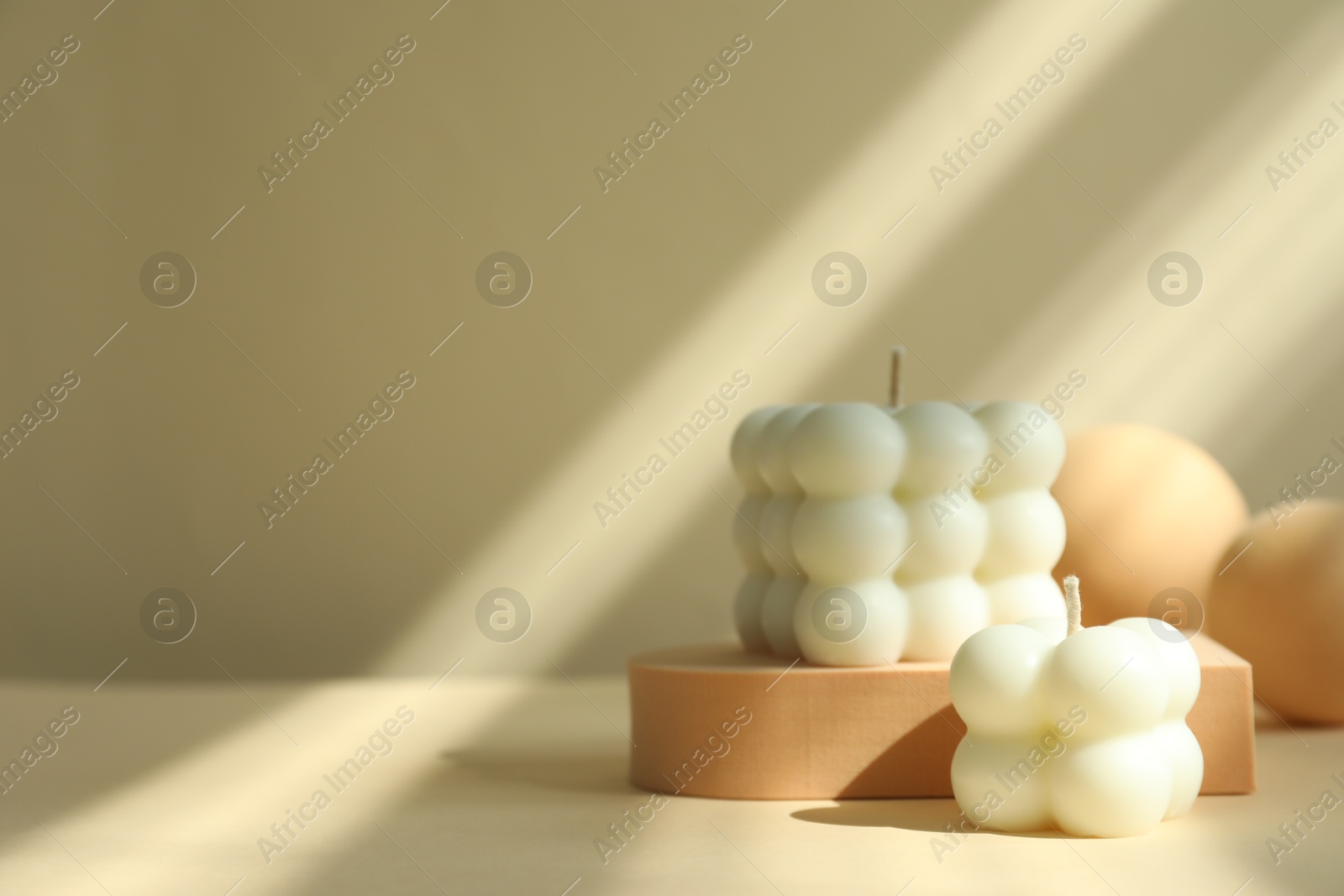 Photo of Beautiful bubble candles and geometric figures on beige background, space for text