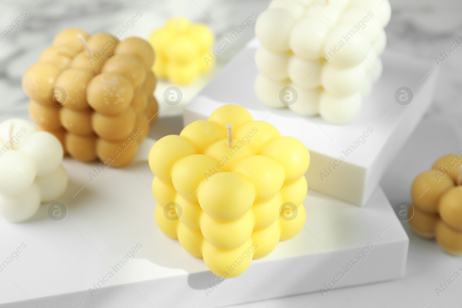 Photo of Beautiful bubble candles and geometric figures on table, closeup