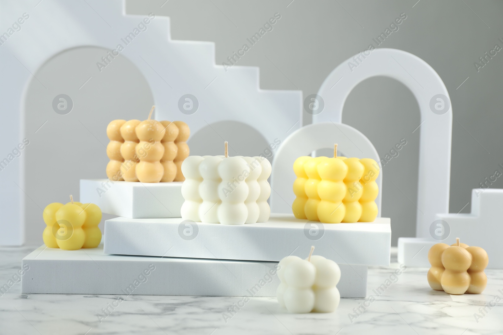 Photo of Beautiful bubble candles and geometric figures on white marble table