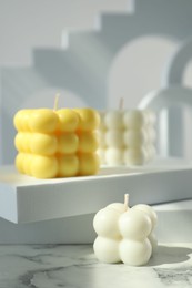 Photo of Beautiful bubble candles and geometric figures on white marble table