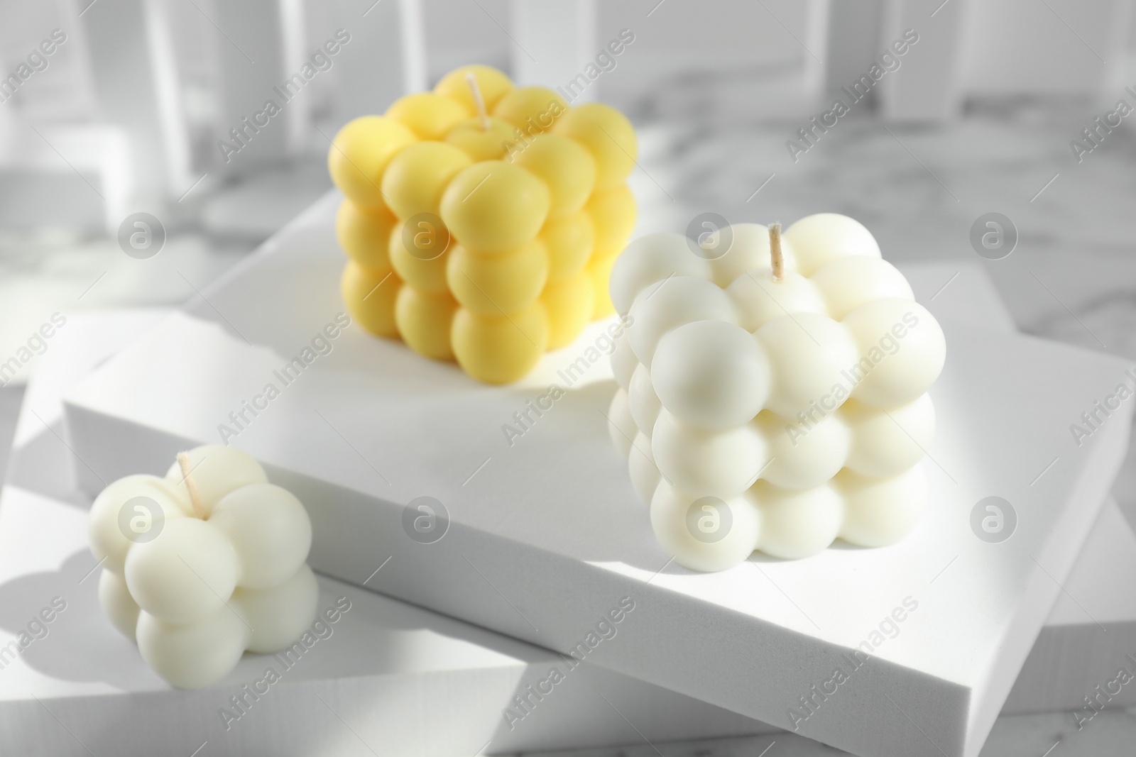 Photo of Beautiful bubble candles and geometric figures on table, closeup