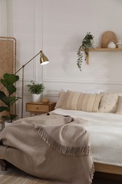 Photo of Stylish bedroom interior with large bed, houseplants and decorative elements