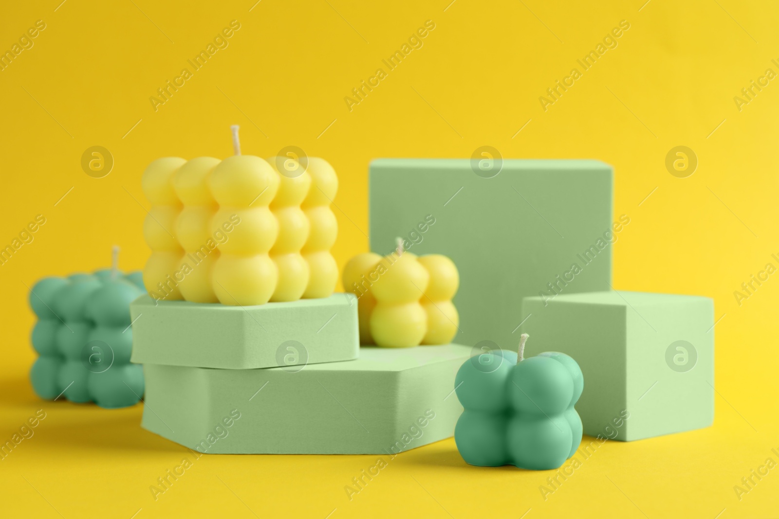 Photo of Beautiful bubble candles and podiums on yellow background