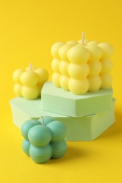 Photo of Beautiful bubble candles and podiums on yellow background