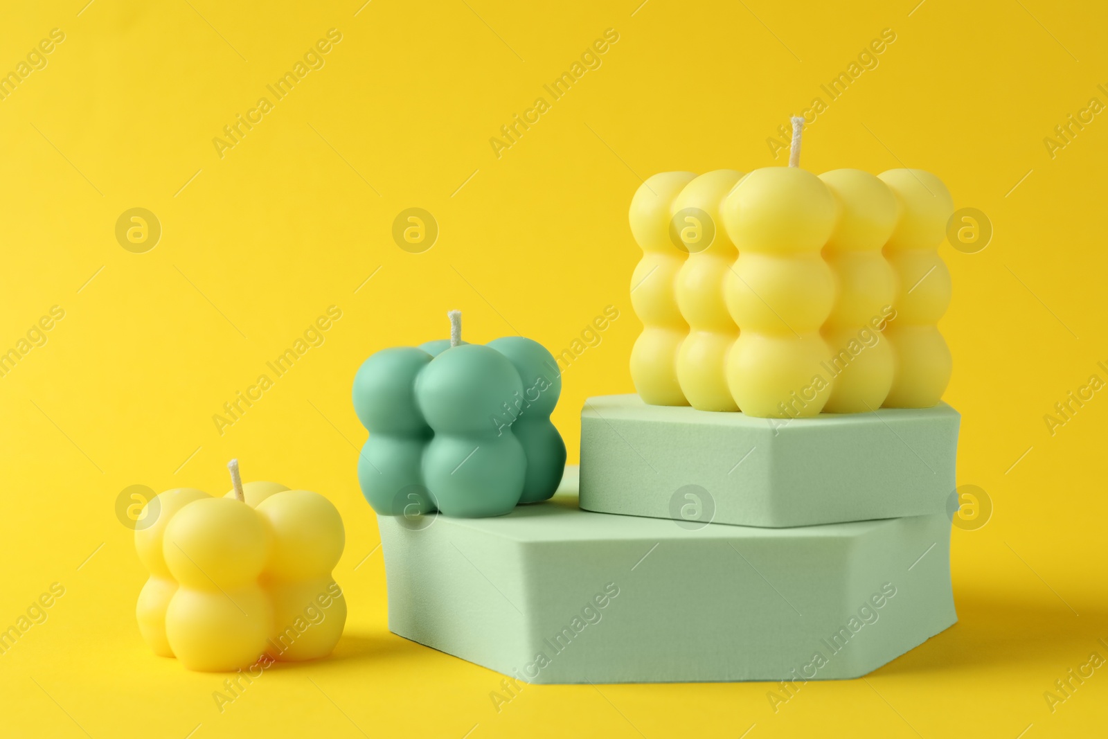 Photo of Beautiful bubble candles and podiums on yellow background