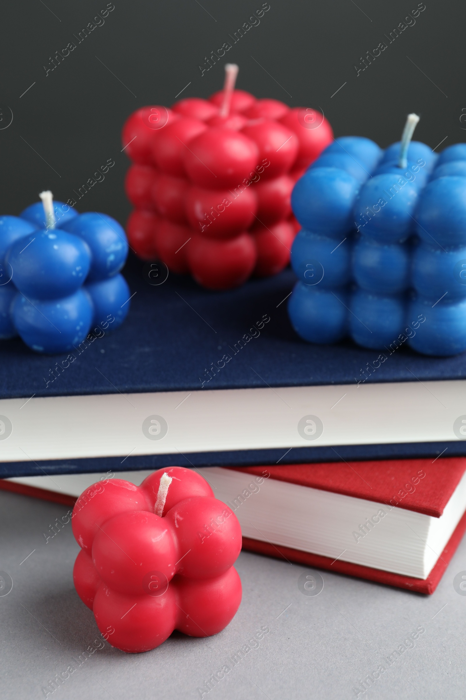 Photo of Beautiful bubble candles and books on grey table, closeup