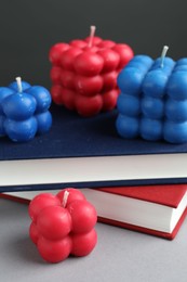 Photo of Beautiful bubble candles and books on grey table, closeup