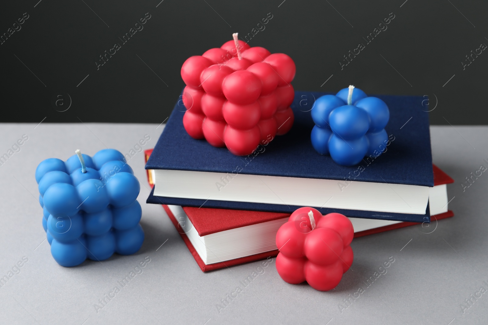 Photo of Beautiful bubble candles and books on grey table