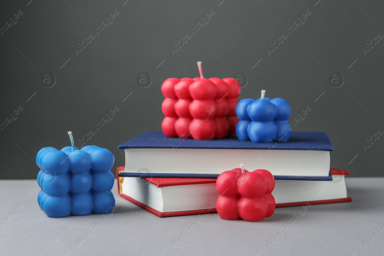 Photo of Beautiful bubble candles and books on grey table