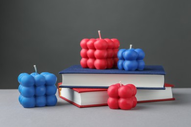 Photo of Beautiful bubble candles and books on grey table