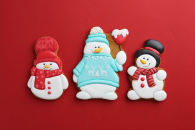 Photo of Tasty Christmas cookies in shape of snowman on red background, flat lay