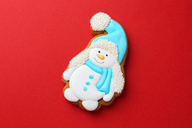 Photo of Tasty Christmas cookie in shape of snowman on red background, top view