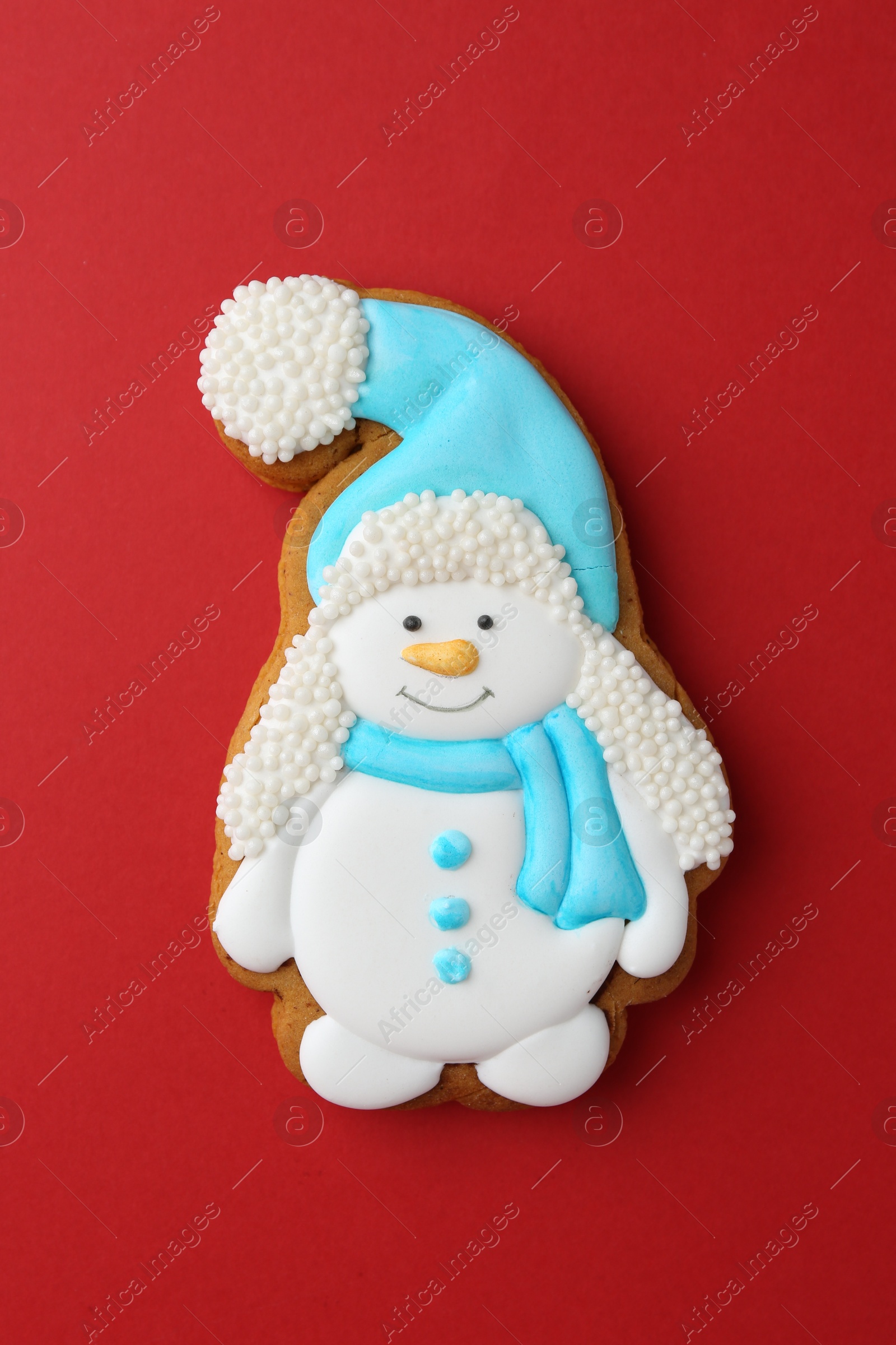 Photo of Tasty Christmas cookie in shape of snowman on red background, top view