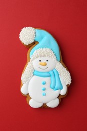 Photo of Tasty Christmas cookie in shape of snowman on red background, top view