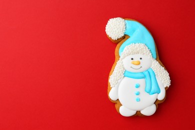 Photo of Tasty Christmas cookie in shape of snowman on red background, top view. Space for text