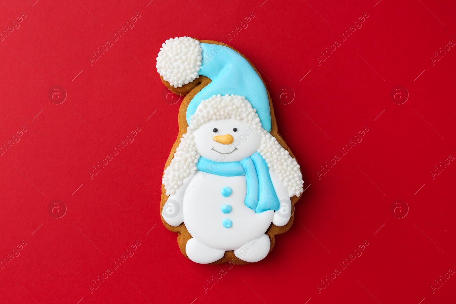 Photo of Tasty Christmas cookie in shape of snowman on red background, top view