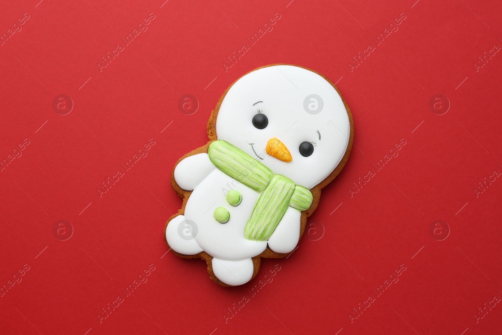 Photo of Tasty Christmas cookie in shape of snowman on red background, top view