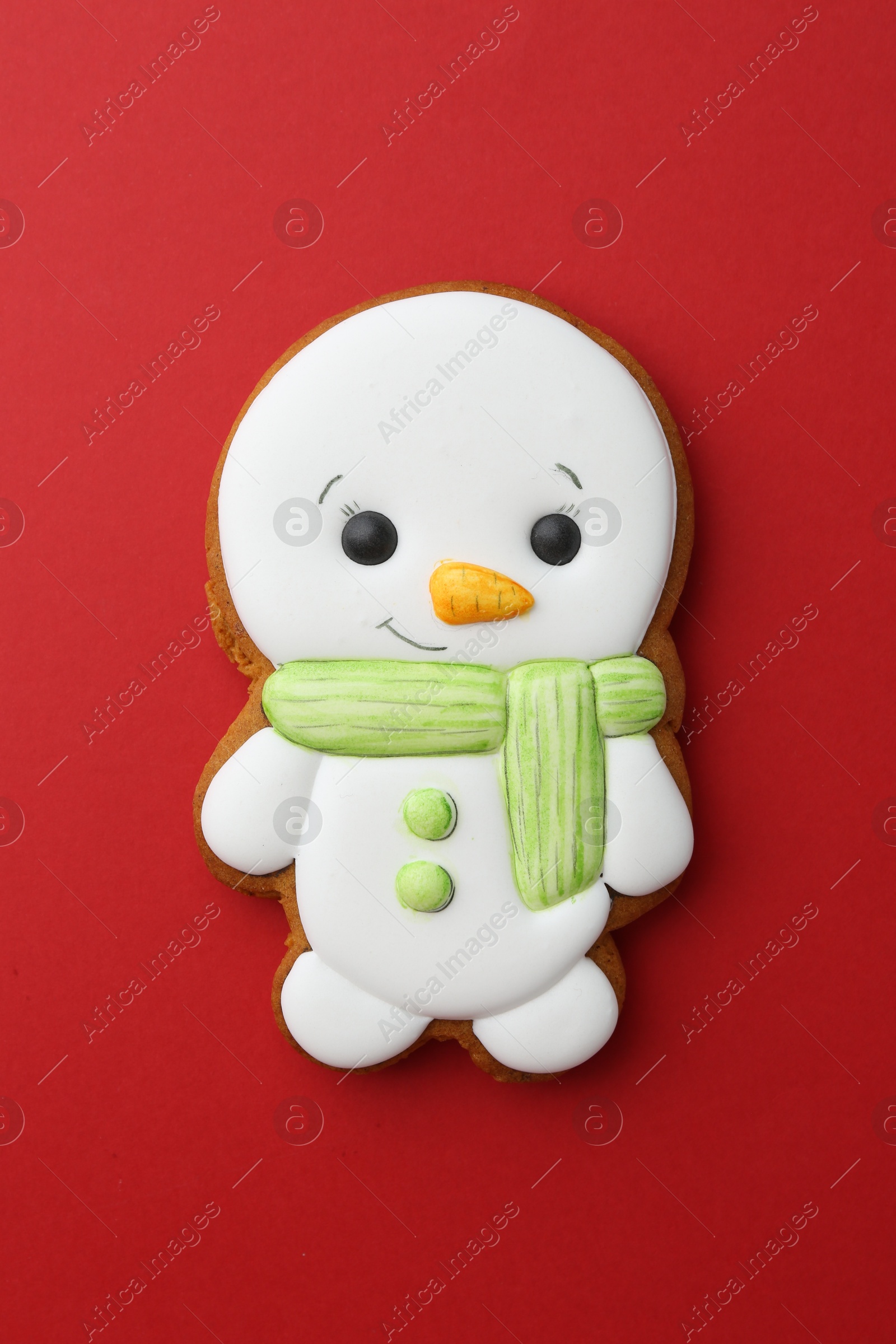 Photo of Tasty Christmas cookie in shape of snowman on red background, top view