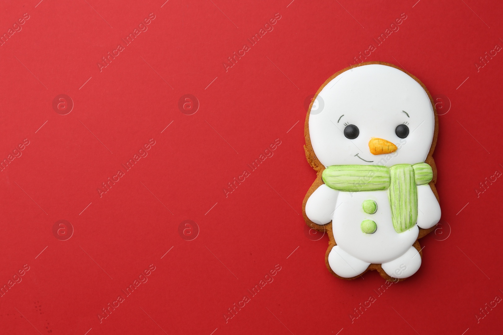 Photo of Tasty Christmas cookie in shape of snowman on red background, top view. Space for text