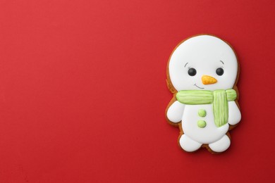 Photo of Tasty Christmas cookie in shape of snowman on red background, top view. Space for text