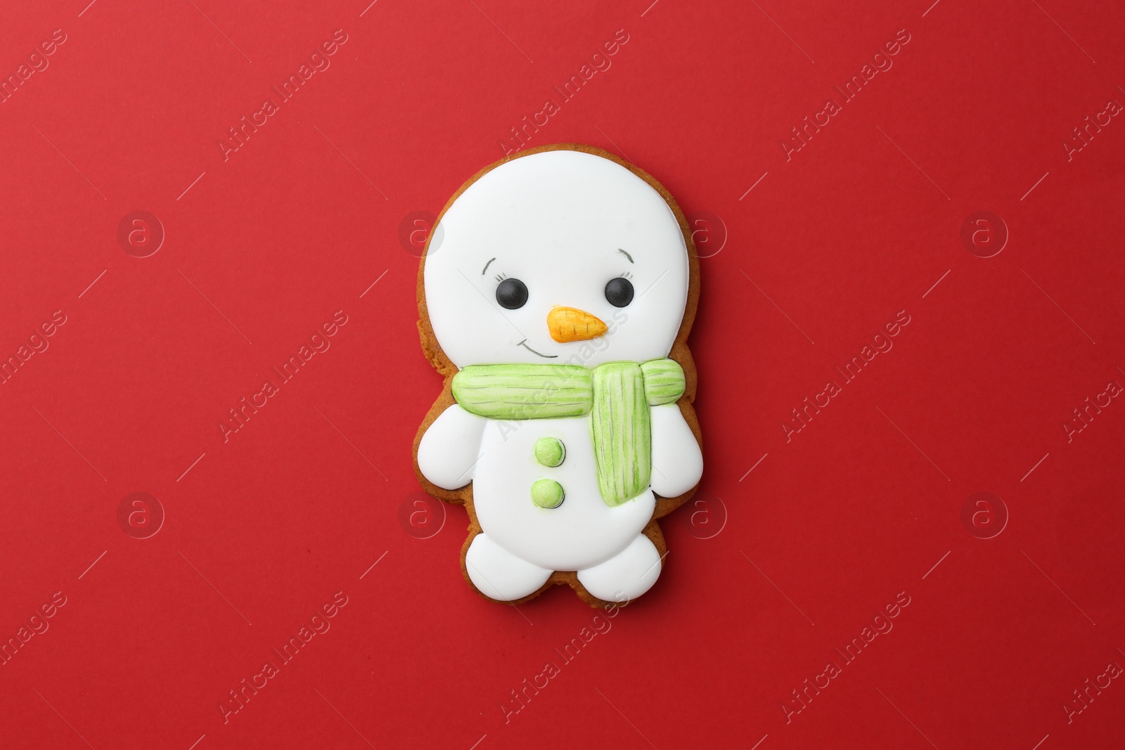 Photo of Tasty Christmas cookie in shape of snowman on red background, top view