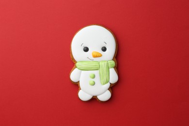 Photo of Tasty Christmas cookie in shape of snowman on red background, top view