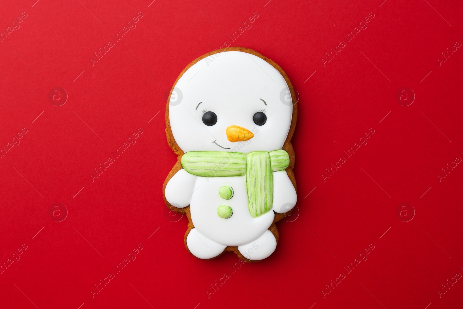 Photo of Tasty Christmas cookie in shape of snowman on red background, top view