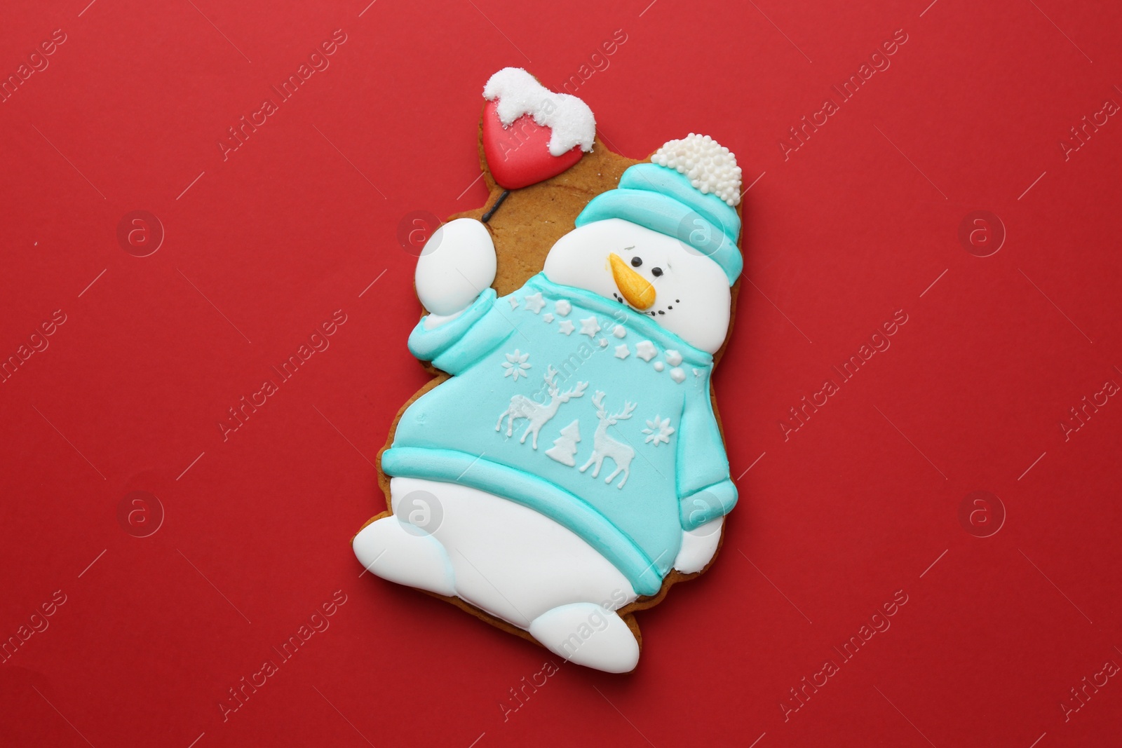 Photo of Tasty Christmas cookie in shape of snowman on red background, top view