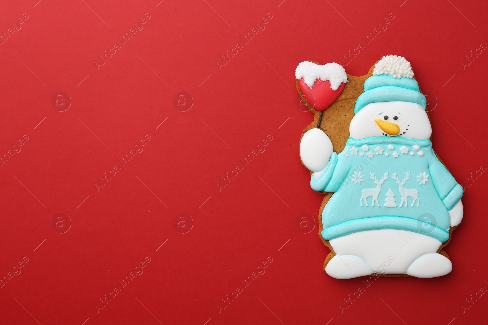 Photo of Tasty Christmas cookie in shape of snowman on red background, top view. Space for text