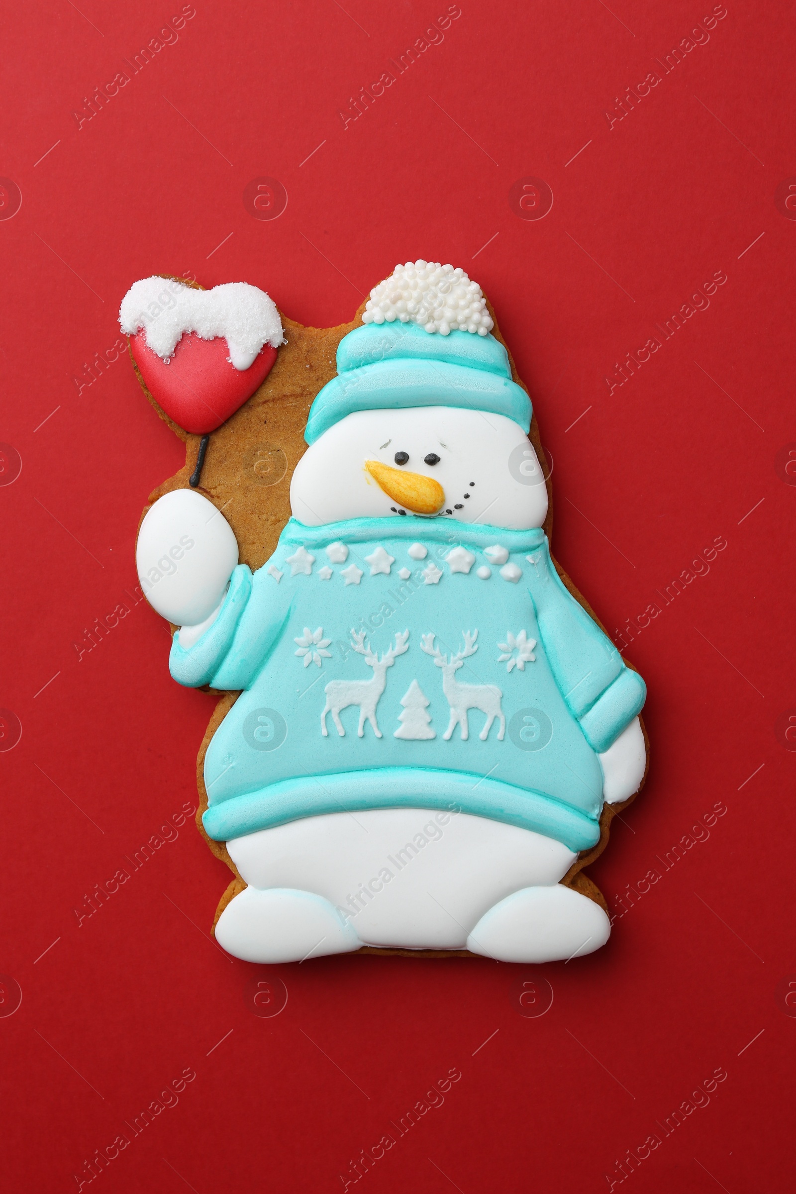 Photo of Tasty Christmas cookie in shape of snowman on red background, top view