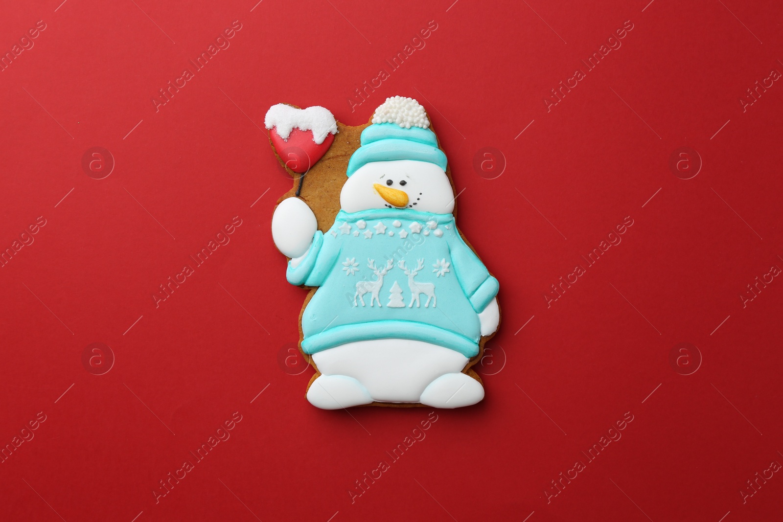 Photo of Tasty Christmas cookie in shape of snowman on red background, top view