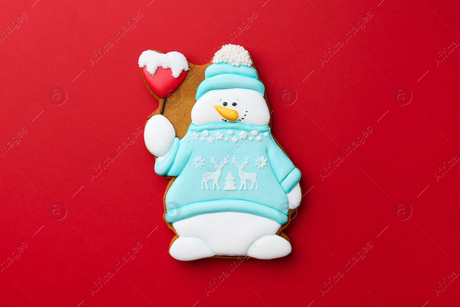 Photo of Tasty Christmas cookie in shape of snowman on red background, top view