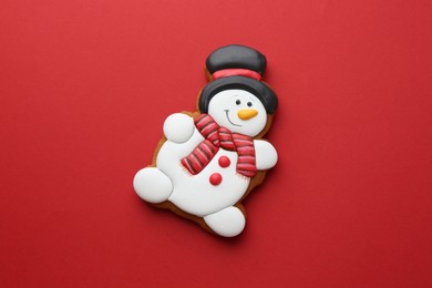 Photo of Tasty Christmas cookie in shape of snowman on red background, top view