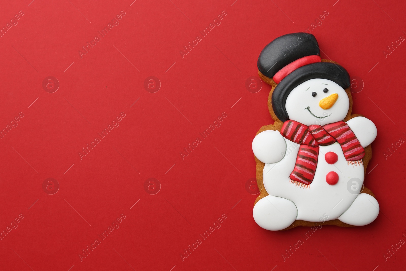 Photo of Tasty Christmas cookie in shape of snowman on red background, top view. Space for text